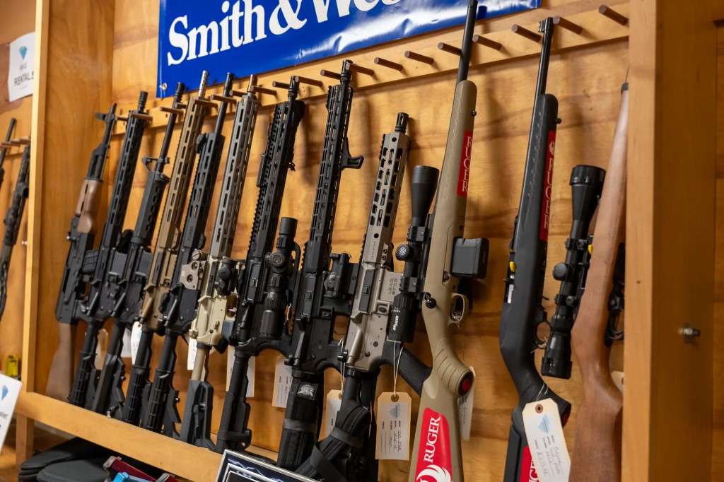 Pro shop rifle wall with modern sporting rifles, bolt-actions, and retail signage
